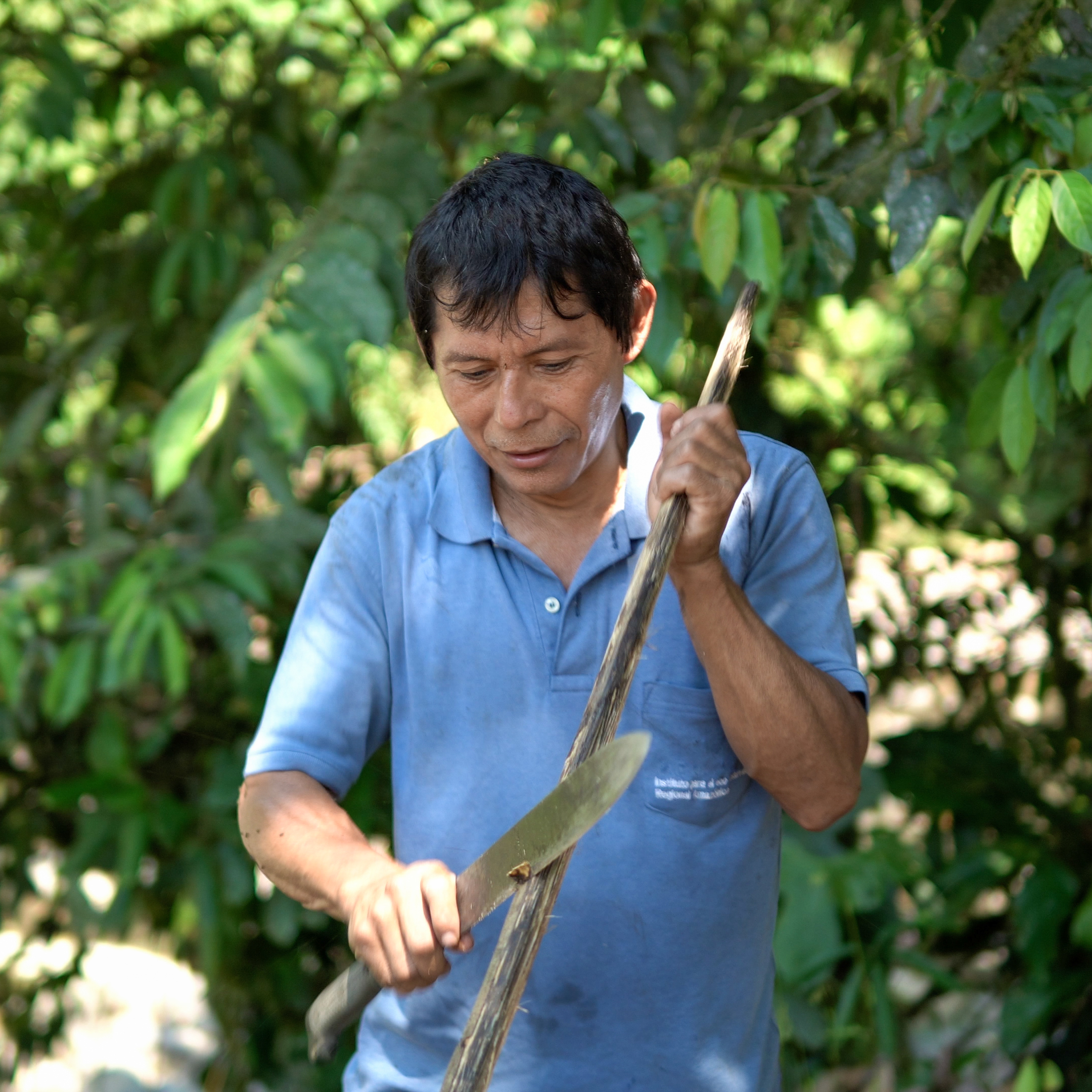 Hombre indígena kichwa del Amazonas preparando una lanza tradicional con su machete durante nuestros viajes culturales inmersivos