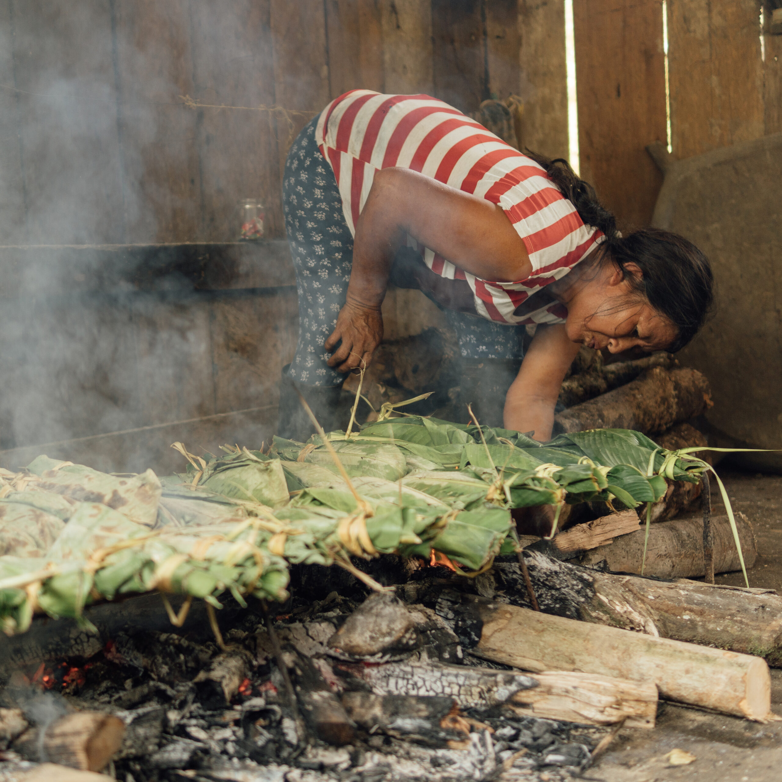 Mujer indígena kichwa preparando comida tradicional en las brasas de un fuego de manera tradicional
