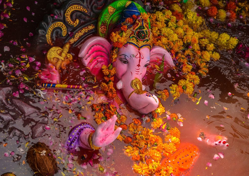 El dios elefante Ganesh cubierto de collares de flores descansa en el río.